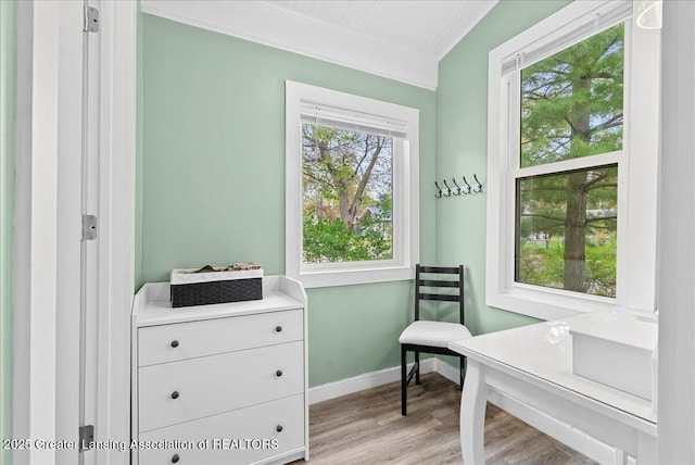 living area with baseboards, ornamental molding, and light wood-style floors