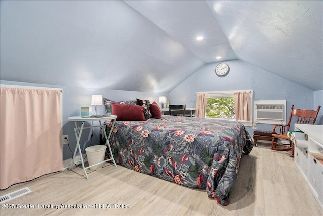 bedroom featuring vaulted ceiling, wood finished floors, visible vents, and a wall mounted air conditioner