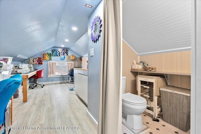 bathroom featuring baseboards, wood finished floors, vaulted ceiling, and toilet