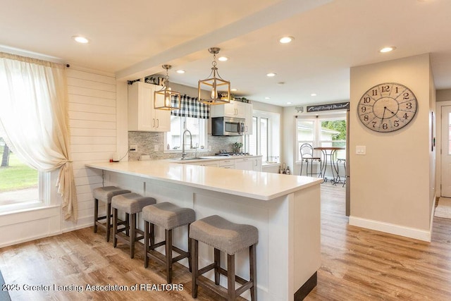 1061 E Sherwood Rd, Williamston, MI 48895 - kitchen with stainless steel appliances, a sink, a kitchen bar, light wood-type flooring, and recessed lighting