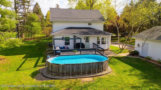 1061 E Sherwood Rd, Williamston, MI 48895 - back of house with an outdoor pool, a wooden deck, a lawn, and a shingled roof