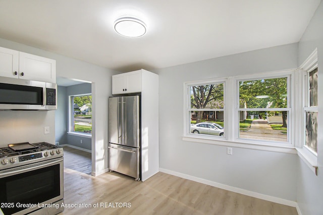 kitchen featuring light wood-type flooring, baseboards, white cabinets, and stainless steel appliances