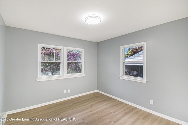 spare room featuring baseboards and wood finished floors