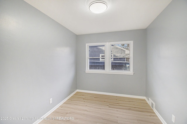 spare room featuring baseboards, light wood finished floors, and visible vents