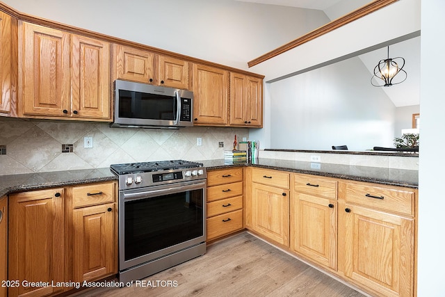 6032 Vienna Way, Lansing, MI 48917 - kitchen featuring appliances with stainless steel finishes, light wood-type flooring, vaulted ceiling, and dark stone countertops
