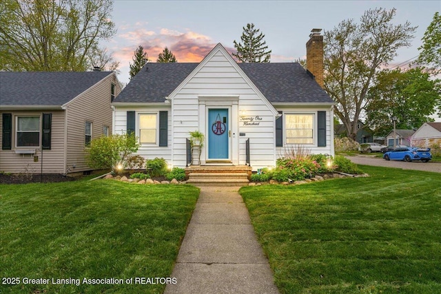 view of front of home featuring roof with shingles, a chimney, and a front yard