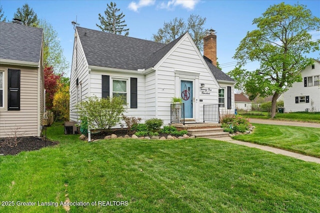 view of front of house featuring a shingled roof, a chimney, and a front yard