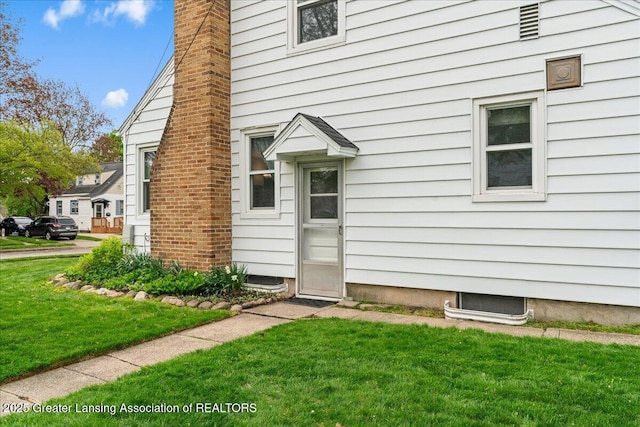property entrance with a yard and a chimney