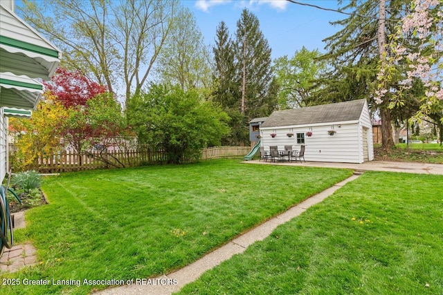 view of yard featuring a playground, an outbuilding, and fence
