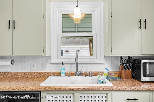 kitchen with pendant lighting, stainless steel microwave, a sink, dishwashing machine, and light countertops