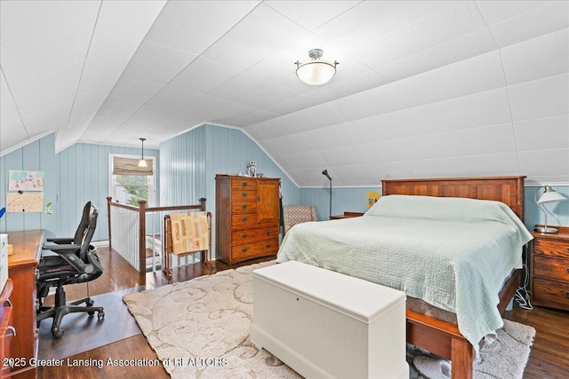 bedroom with wood walls, vaulted ceiling, and wood finished floors