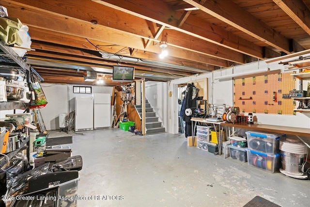 below grade area featuring freestanding refrigerator, stairway, and a workshop area