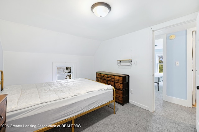 bedroom featuring lofted ceiling, light carpet, and baseboards