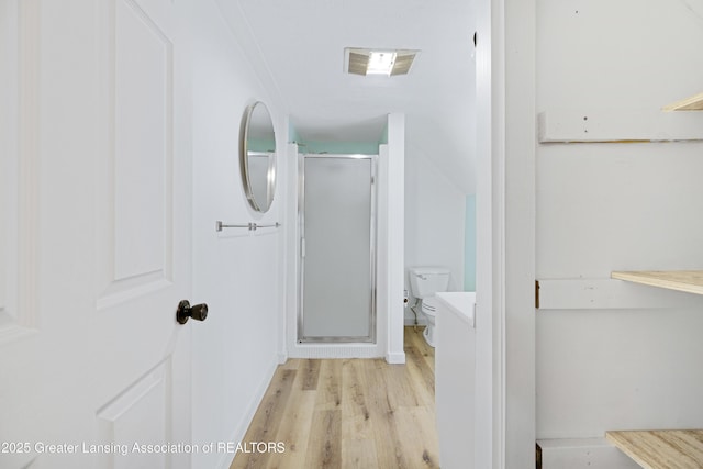 full bath featuring toilet, visible vents, wood finished floors, and a shower stall