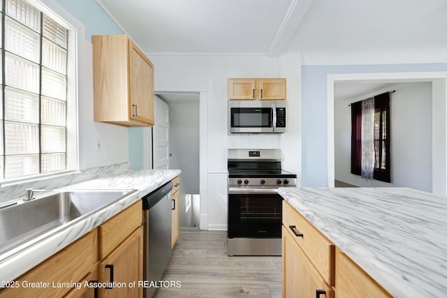 kitchen with a sink, stainless steel appliances, light brown cabinets, light wood-style floors, and light stone counters