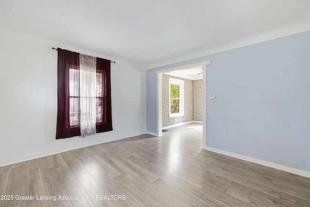 spare room with baseboards and wood finished floors