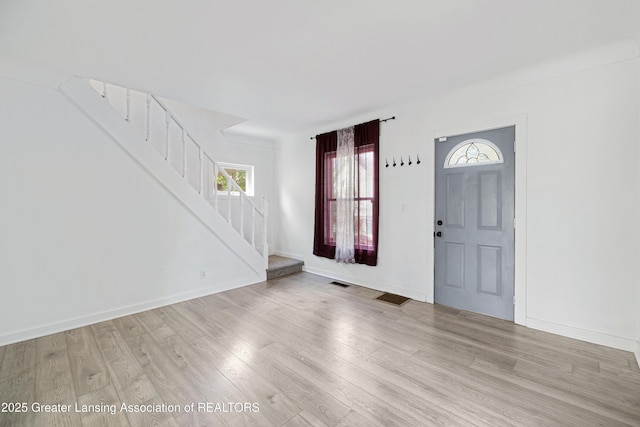 foyer with stairway, baseboards, visible vents, and light wood-style floors