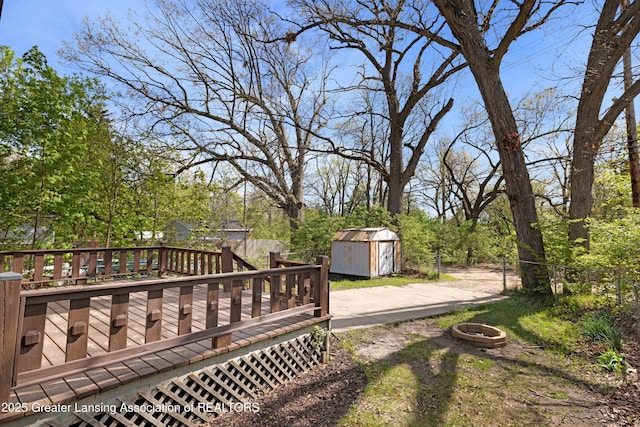 view of yard with an outbuilding, fence, an outdoor fire pit, a deck, and a storage unit