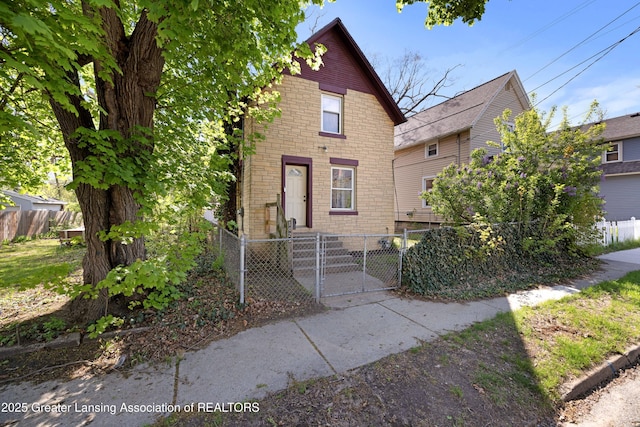 traditional-style home with a fenced front yard, brick siding, and a gate