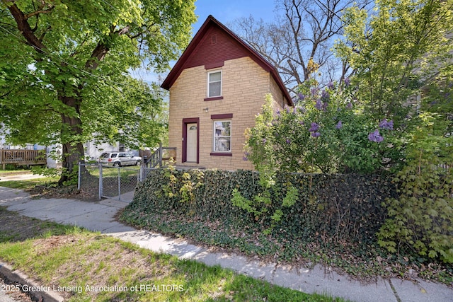 view of front of property featuring a gate, fence, and brick siding