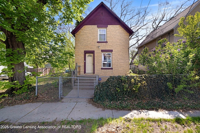 traditional-style house featuring a gate, brick siding, and a fenced front yard
