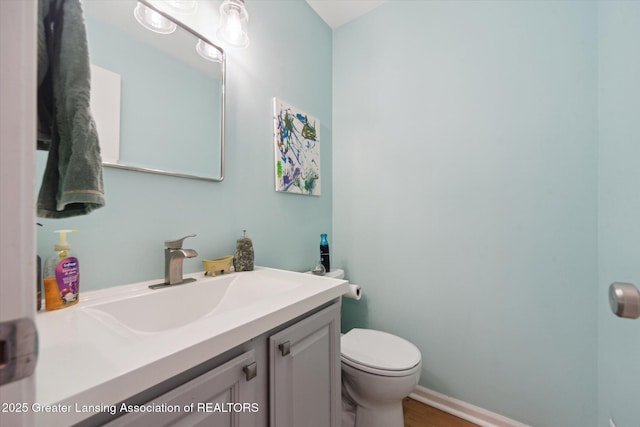 1212 Sandhill Dr, Dewitt, MI 48820 - half bathroom with vanity, toilet, baseboards, and wood finished floors
