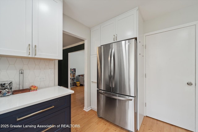 1212 Sandhill Dr, Dewitt, MI 48820 - kitchen featuring freestanding refrigerator, light wood-style floors, white cabinetry, and decorative backsplash