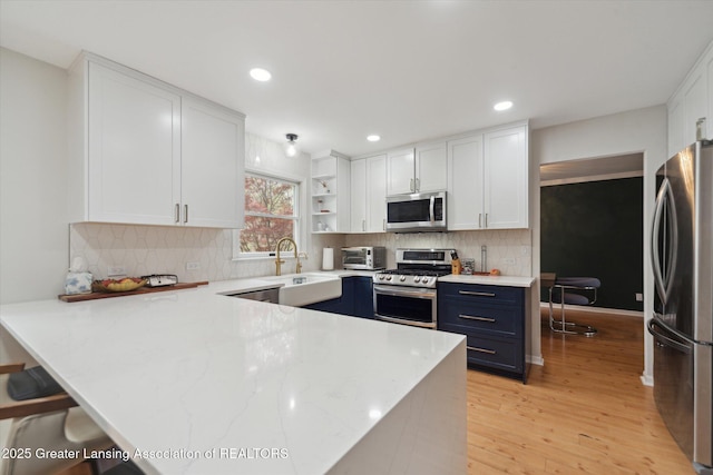 1212 Sandhill Dr, Dewitt, MI 48820 - kitchen with a peninsula, stainless steel appliances, blue cabinets, white cabinets, and light wood-style floors