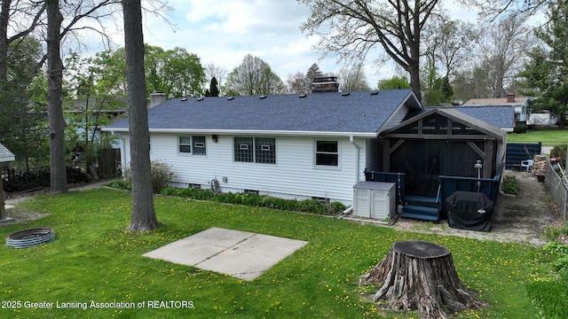 back of property featuring a shingled roof, a yard, an outdoor fire pit, and a chimney