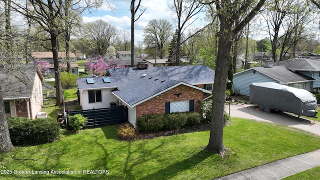 view of front of house featuring fence, a shingled roof, brick siding, and a front yard