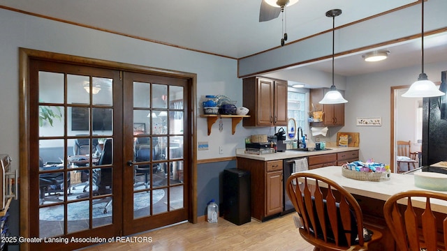 kitchen with light wood finished floors, french doors, a sink, decorative light fixtures, and light countertops