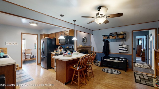 kitchen featuring a ceiling fan, a breakfast bar, light wood-type flooring, black appliances, and light countertops