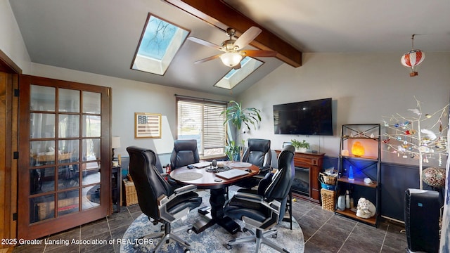 home office featuring ceiling fan, dark tile patterned floors, and vaulted ceiling with skylight