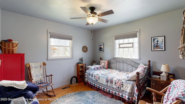bedroom featuring a ceiling fan, visible vents, light wood-style flooring, and baseboards