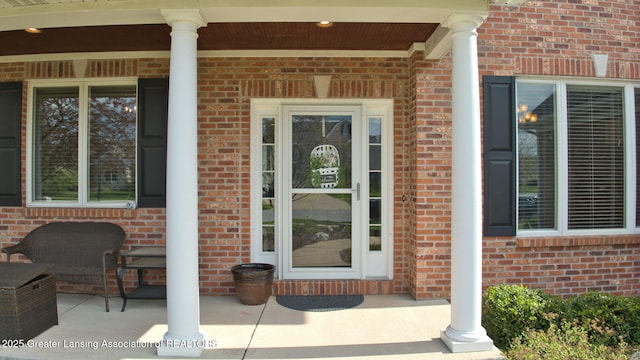 view of exterior entry with covered porch and brick siding