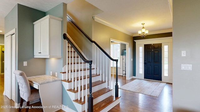 entryway with stairway, a notable chandelier, a healthy amount of sunlight, and wood finished floors