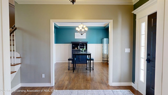 foyer featuring crown molding, baseboards, an inviting chandelier, and wood finished floors