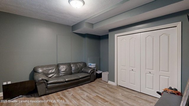 living room with light wood-style flooring, a textured ceiling, and baseboards