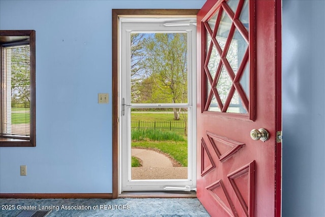doorway featuring plenty of natural light and baseboards