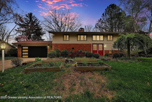 mid-century inspired home featuring an attached garage, brick siding, driveway, a chimney, and a vegetable garden