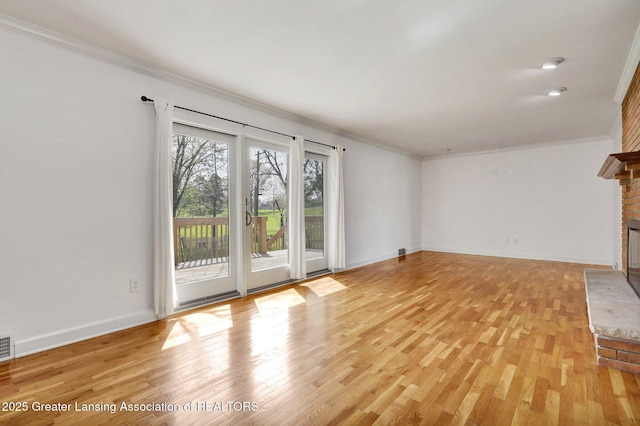 unfurnished living room with crown molding, a fireplace, and light wood-style flooring