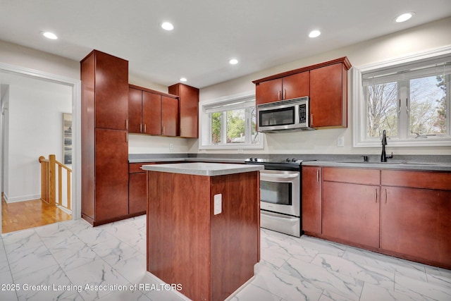 kitchen featuring recessed lighting, a center island, marble finish floor, and appliances with stainless steel finishes