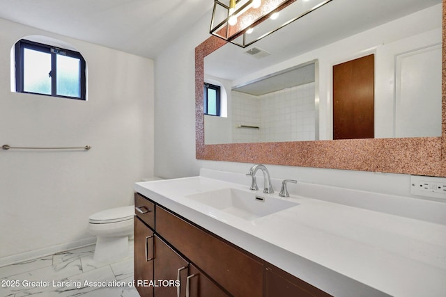 bathroom with toilet, marble finish floor, vanity, and plenty of natural light