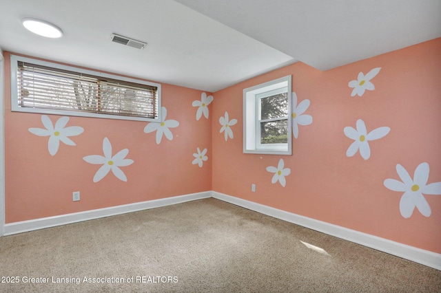 spare room with a wealth of natural light, visible vents, and carpet floors