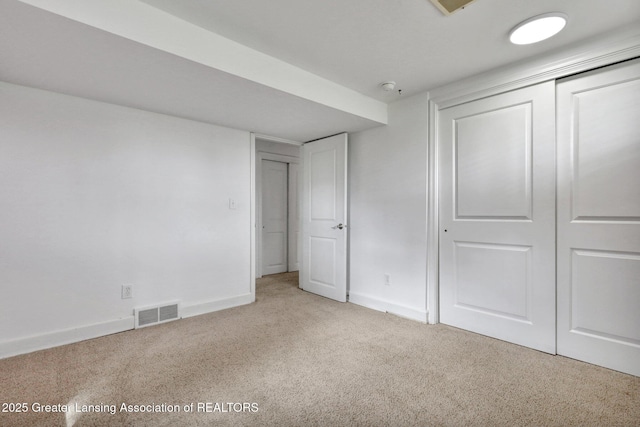 unfurnished bedroom featuring light colored carpet, baseboards, a closet, and visible vents