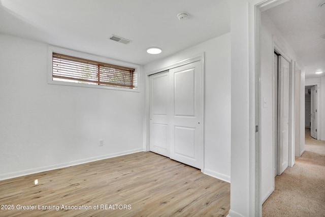 unfurnished bedroom with baseboards, a closet, light wood-style flooring, and visible vents