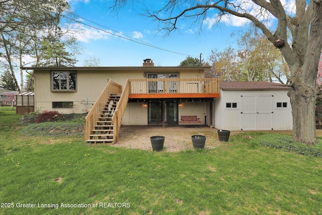 rear view of house with stairway, a wooden deck, and a lawn