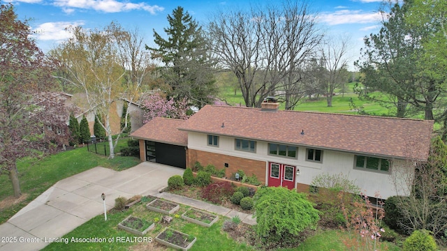 exterior space featuring a chimney, driveway, brick siding, a shingled roof, and a front lawn