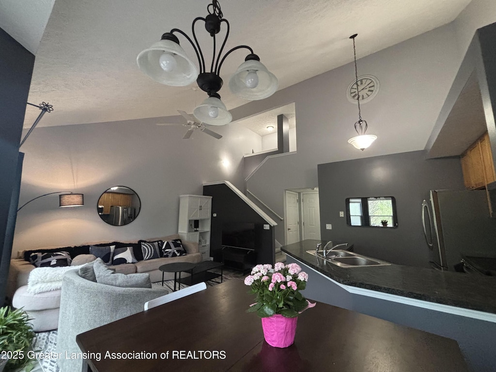 dining space with ceiling fan and high vaulted ceiling