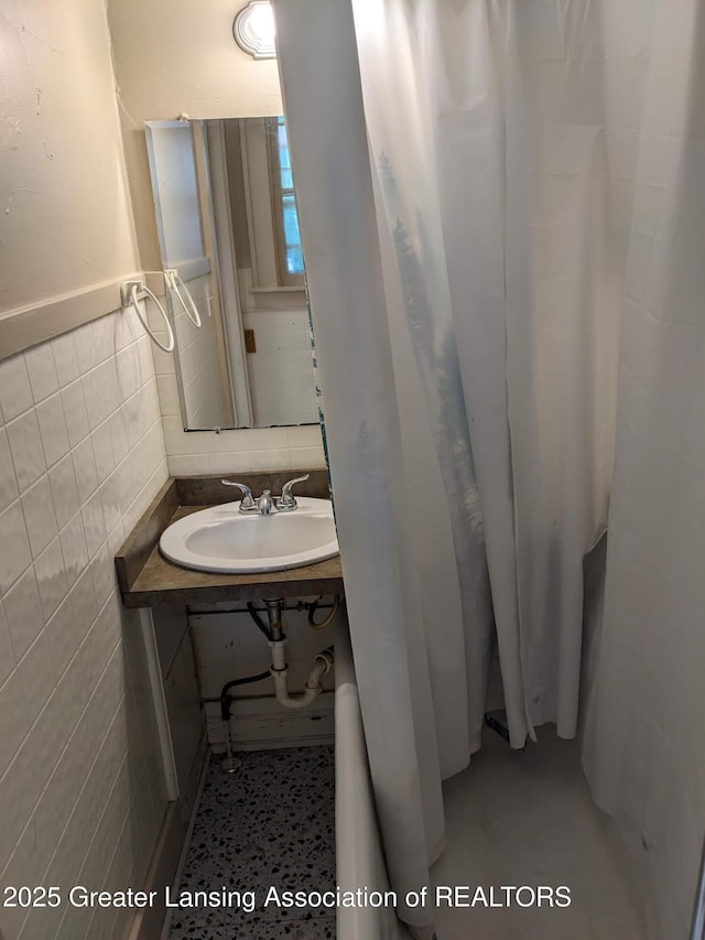 bathroom featuring tile walls and a sink